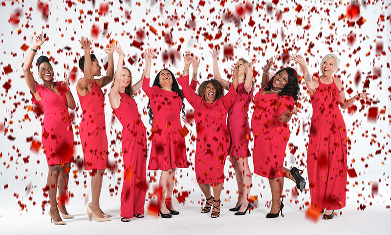 Photo of group of women in red throwing red confetti in the air